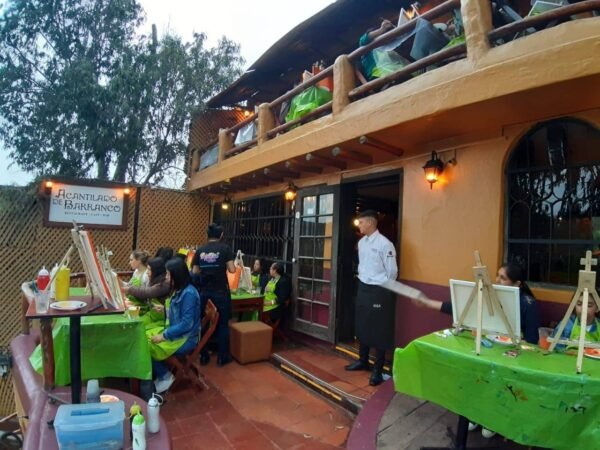 Foto de sesión de pintura Paint in Bar realizada en el Acantilado de Barranco, Lima, Perú. Se ve el artista parado y los clientes sentados, todos pintando